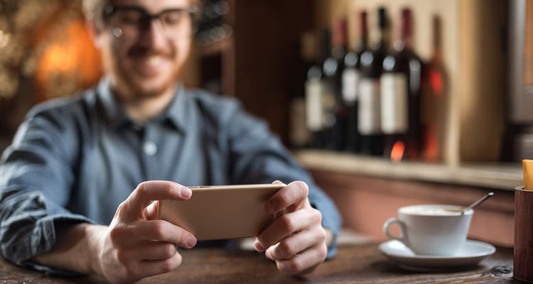 41802448 - cheerful guy at the restaurant using a mobile phone, hands close up