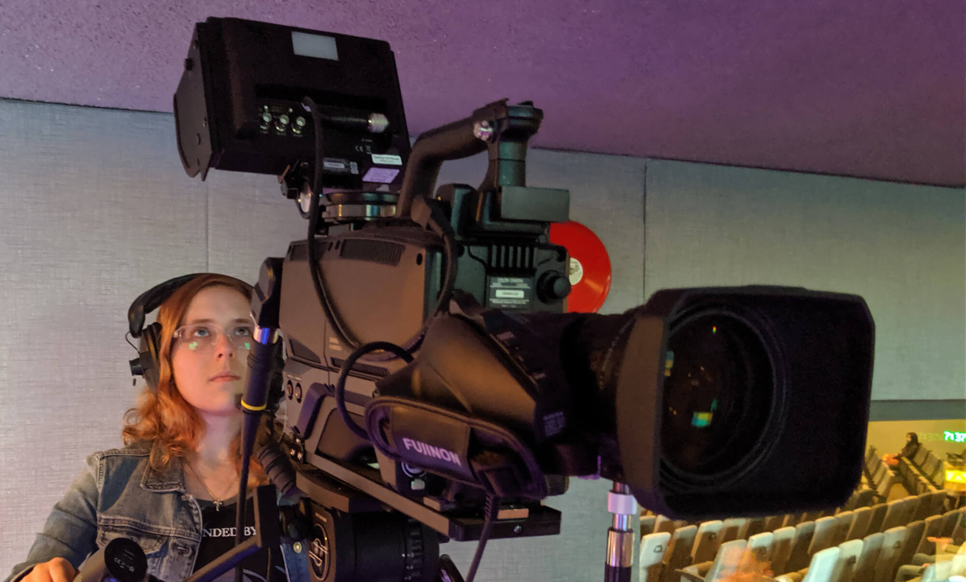 A woman mans a large camera during a church service